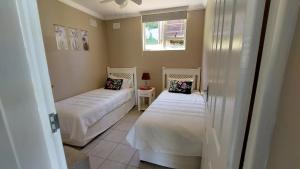 a room with two beds and a window at Poolside Guest House in Port Shepstone