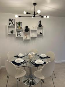 une salle à manger avec une table en verre et des chaises blanches dans l'établissement Centrally Located Flat in London with Free Parking, à Edgware