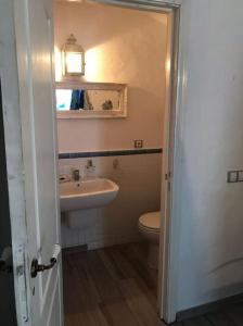 uma casa de banho com um lavatório, um WC e um espelho. em CASITA LINDA em Facinas