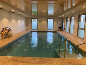 uma grande piscina interior com piso em madeira e janelas em Domitys Villa Kera em Limoges