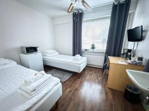 a hotel room with two beds and a sink at Hostelli Matkustajakoti in Kuopio