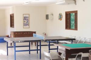 two ping pong tables in a room with chairs at Pousada Canto da Enseada in Nazaré Paulista
