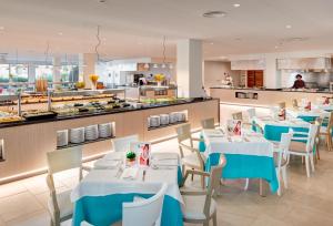 a restaurant with blue tables and chairs and a kitchen at Grupotel Mallorca Mar in Cala Bona