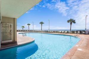 a large swimming pool with palm trees and the ocean at Tradewinds Unit 608 in Orange Beach