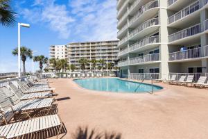 a large apartment building with a swimming pool and lounge chairs at Tradewinds Unit 608 in Orange Beach