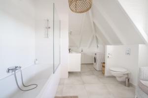 a white bathroom with a toilet and a bath tub at Luxe pleine vue mer et plage in Saint-François +26 photos