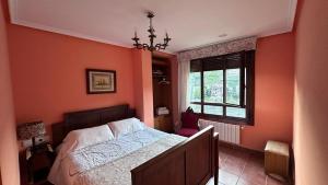 um quarto com paredes cor de laranja, uma cama e uma janela em Casa Alpargateiro em Os Peares