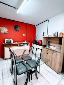 a table and chairs in a kitchen with red walls at Kaleidoscopio Hostel in Sao Paulo