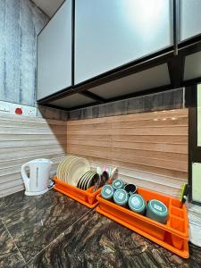 an orange tray with dishes on a kitchen counter at Blossom - Casa Kayangan Meru Ipoh by GOSWELL in Ipoh