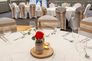 una mesa con una botella de vino y una rosa roja en Charnwood Arms, en Coalville