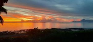 a sunset over a body of water with the sky at Kahaia beach home with pool amazing seafront black sand beach and reef in Paea