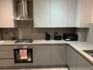 a kitchen with white cabinets and a stove and a microwave at Stunning 2-Bed Apartment in Barking in Barking