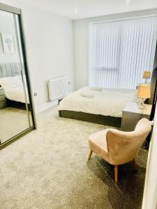 a bedroom with a bed and a mirror and a chair at Stunning 2-Bed Apartment in Barking in Barking