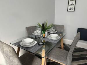 a dining room table with chairs and a glass table with plates at Lowther House -2 Bed Apartment in Whitehaven