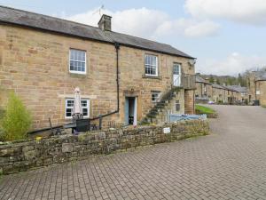 a brick building with a stone wall next to a street at Toad Cottage in Matlock