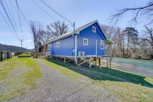 una casa azul sentada a orillas de un río en Cozy Smoky Mountain River Camp with River Tubes!, en Walland