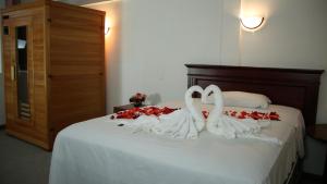 two swans in white towels on a bed with roses at HOSTERIA RANCHO SANTA FE in Cotacachi