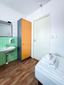 a bathroom with a bed and a sink and a mirror at Hostelli Matkustajakoti in Kuopio