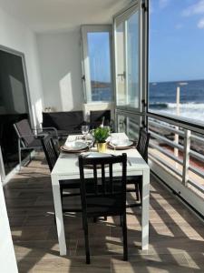een witte tafel en stoelen op een balkon met uitzicht op de oceaan bij La Terraza del Mar in Puertito de Güímar