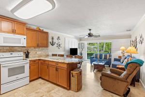 a kitchen with wooden cabinets and a living room at Waterfront Pools and Cabana by Duck Keys Marathon in Marathon