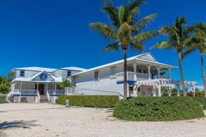 a white house with palm trees in front of it at Waterfront Pools and Cabana by Duck Keys Marathon in Marathon