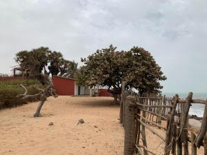 a fence on a sandy beach near the ocean at Chambre en bord de mer …(pied dans l’eau) in Ngalou Sessène