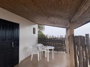 Ngalou SessèneChambre en bord de mer …(pied dans l’eau)的有窗户的房间里有一张白色的桌子和几把椅子