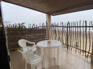 Ngalou SessèneChambre en bord de mer …(pied dans l’eau)的阳台上有一张白色的桌子和椅子，可以欣赏到大海