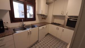 uma cozinha com armários brancos, um lavatório e uma janela em Apartamento en el centro de Puigcerda em Puigcerdà