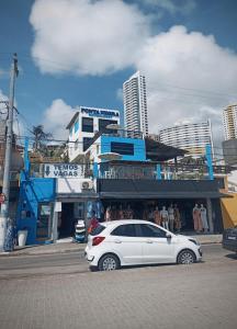 une voiture blanche garée devant un bâtiment dans l'établissement Ponta Negra Suites & Apart, à Natal