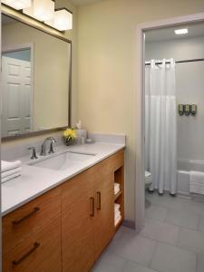 a bathroom with a sink and a mirror and a shower at Avia Residences on Lincoln - Extended Stay in Malvern