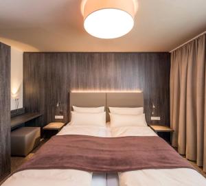 ein Schlafzimmer mit einem großen Bett und einer Holzwand in der Unterkunft MYHOTEL München Olching in Olching