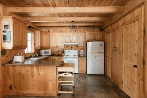 eine Küche mit Holzschränken und einem weißen Kühlschrank in der Unterkunft Le Sunset in Eastman