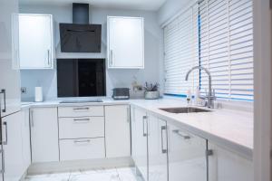 a white kitchen with white cabinets and a sink at Stunning 2-Bed Ground Floor Flat in Birmingham in Birmingham