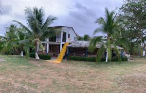 una casa con palmeras y un tobogán amarillo en CABAÑA VILLA DEL COCO, en Arboletes