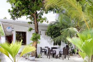a table and chairs in front of a white building at Manta Sky Inn in Dharavandhoo