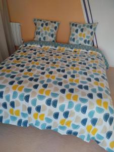 Una cama con un edredón azul y amarillo. en LA BELLE IVOIRE, en Saint-Marcel