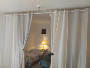 a room with white curtains and a bed and a lamp at LA BELLE IVOIRE in Saint-Marcel