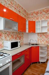 cocina con armarios rojos y microondas en 2 комнатная квартира, по суточно, напротив ТД Сырымбет, en Kokshetau