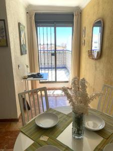 una mesa de comedor con un jarrón de flores. en CONCEPCIÓN HOUSE HUELVA, pleno centro, GARAJE en el propio edificio en Huelva