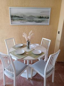 una mesa blanca con 4 sillas y un jarrón de flores en CONCEPCIÓN HOUSE HUELVA, pleno centro, GARAJE en el propio edificio en Huelva