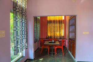Auro Wellness Castle في بونديتْشيري: غرفة طعام مع طاولة وكراسي حمراء