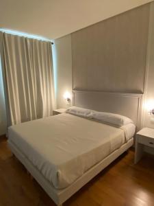 a white bed in a bedroom with two lamps at Hotel Santa Ana in La Carlota