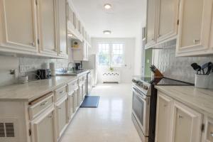 a kitchen with white cabinets and a white floor at Cardinal Inn Western Room in Cornwall