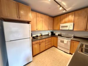 a kitchen with wooden cabinets and a white refrigerator at Flexhome Third Ward 1BR J1 with Gym and Balcony - READ INFO in Milwaukee