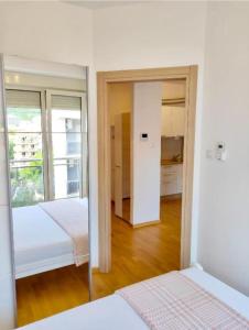 a white bedroom with two beds and a mirror at Apartmani More in Budva