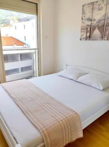 a white bed in a room with a window at Apartmani More in Budva