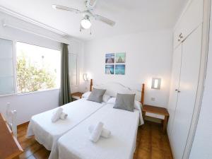 a bedroom with two beds with white sheets and a window at Apartamento 107 Castell Sol CB in Arenal d'en Castell