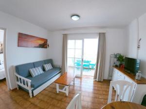 uma sala de estar com um sofá azul e uma mesa em Apartamento 107 Castell Sol CB em Arenal d'en Castell