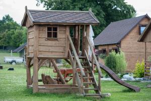 a wooden play house with a slide in a yard at Domki Niegowa in Niegowa